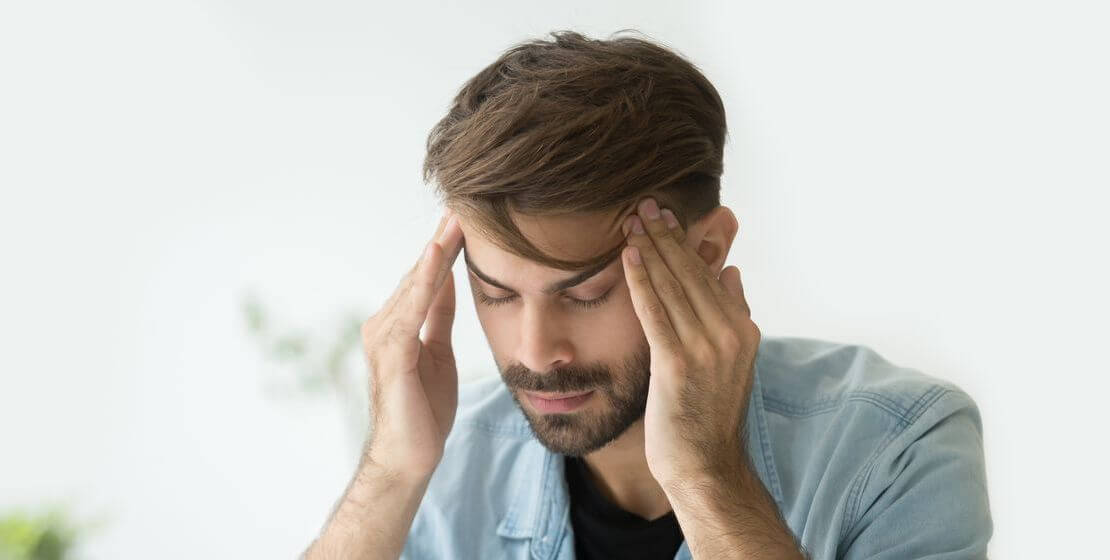 Young man touching temples. Tired exhausted suffering from fatigue, chronic stress or a migraine.