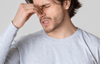 Handsome guy holds nose bridge and suffers from pain