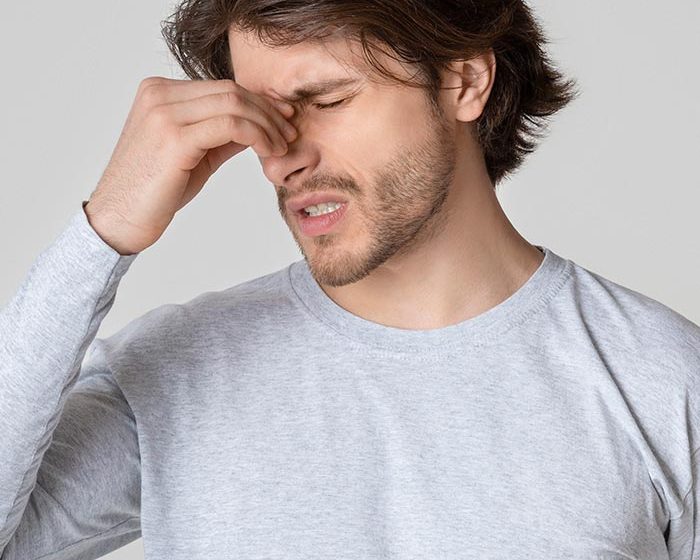 Handsome guy holds nose bridge and suffers from pain