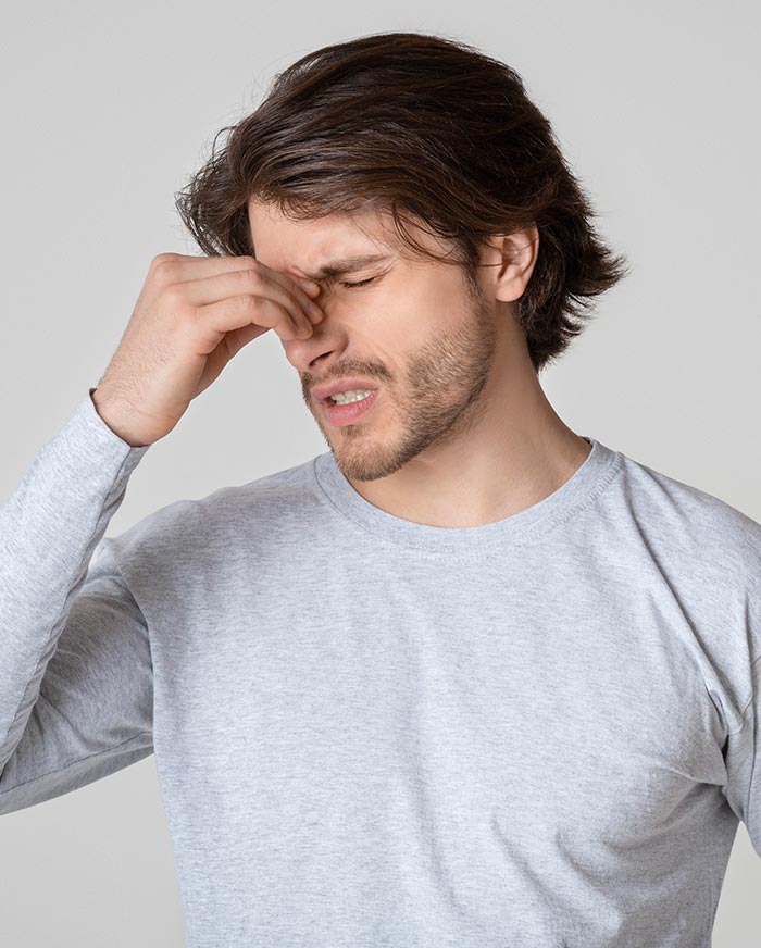 Handsome guy holds nose bridge and suffers from pain