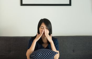 Woman with nasal congestion sitting in her bed.