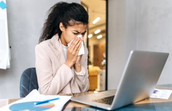 Young businesswoman suffering from runny nose.