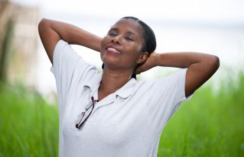 Happy relaxed Afro-American woman breathing deeply while spending time outdoors.