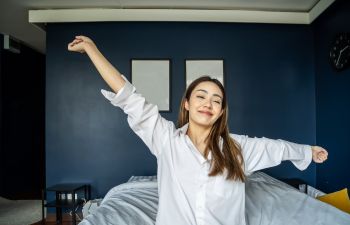 Happy young woman waking up after good sleep.