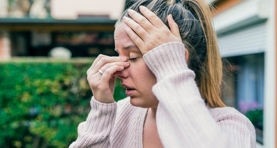 Sinus ache causing very paintful headache. Unhealthy woman in pain. Sharp strong sore. Sinus pain, sinus pressure, sinusitis. Sad woman holding her nose and head because sinus pain